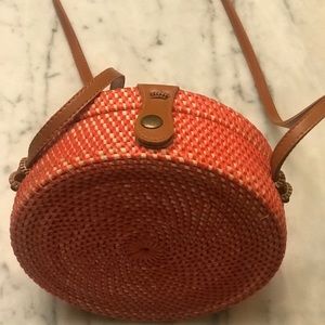 Round burnt orange crossbody wicker canteen bag.